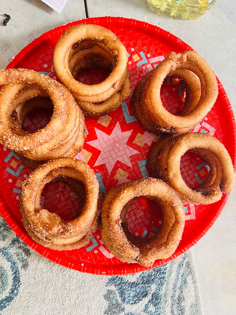 Delicious sugar-coated dough rings arranged on a traditional red platter, perfect for festivals.